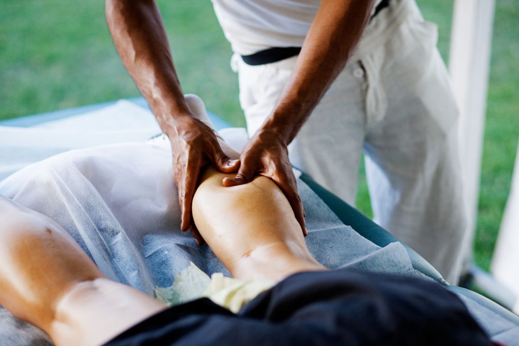Person ligger på maven på en massagebriks og får masseret sin venstre læg.