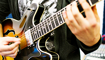 Nærbillede af en elev, der spiller guitar.