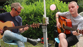 Elev og lærer spiller guitar i IBOS gårdhave