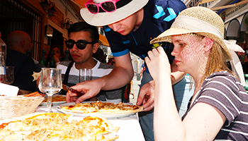 3 elever spiser pizza i solen på studietur