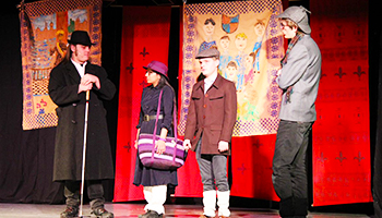 Foto fra teaterforestilling, hvor 4 personer er på scenen i kostumer.