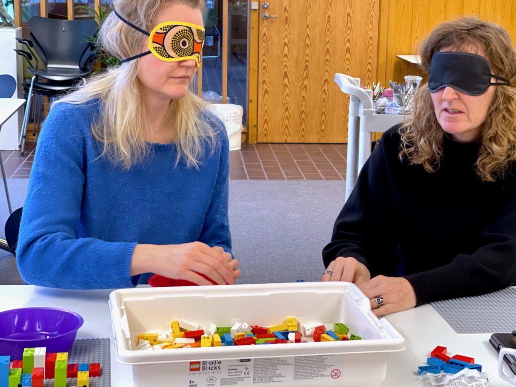To deltagere med bind for øjnene og lego foran sig
