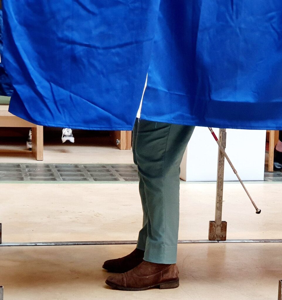 Foto af Tinas ben og mobilitystok, alene i stemmeboksen