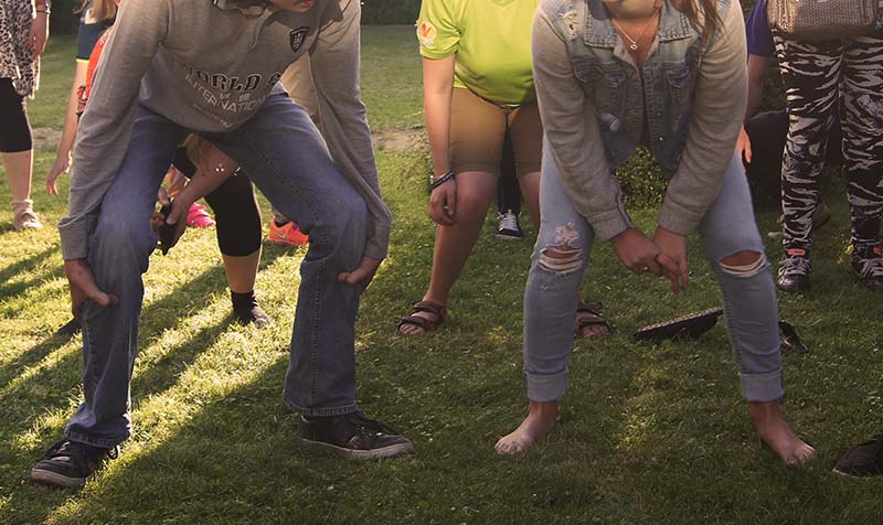 en solbeskinnet græsplæne med unge, der står i hug i en fælles aktivitet
